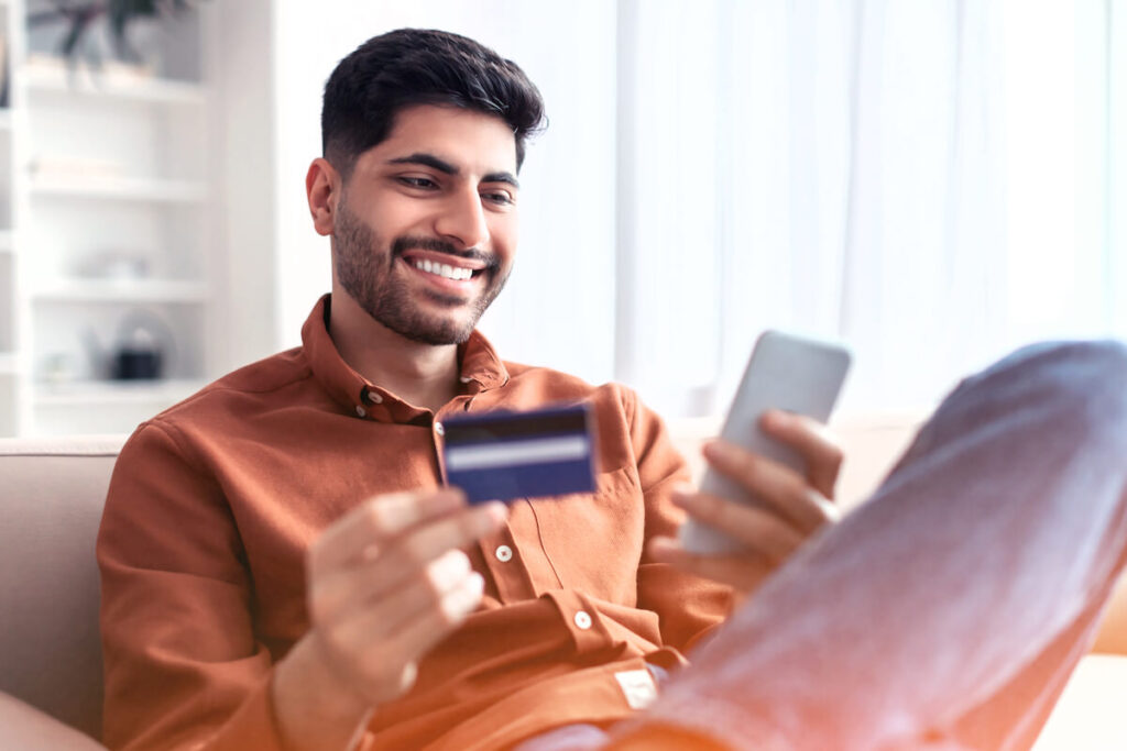 man looking at phone with credit card blurred