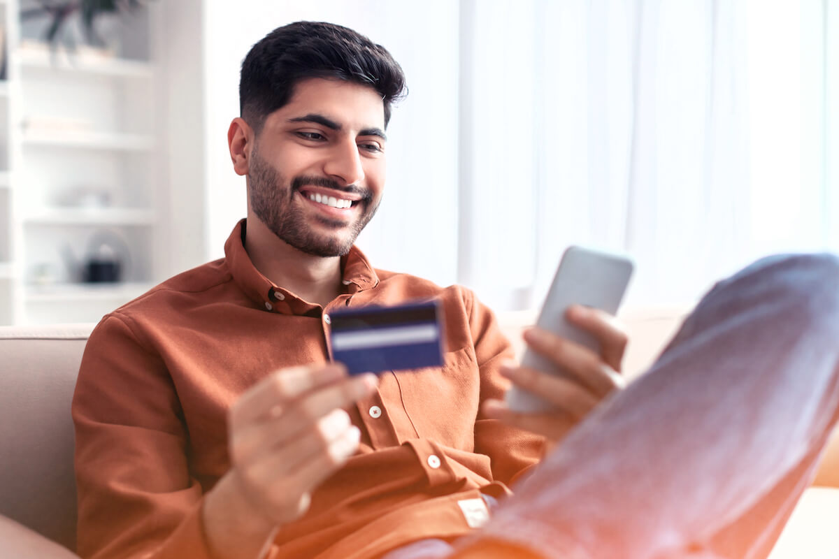 young man looking at phone with credit card blurred