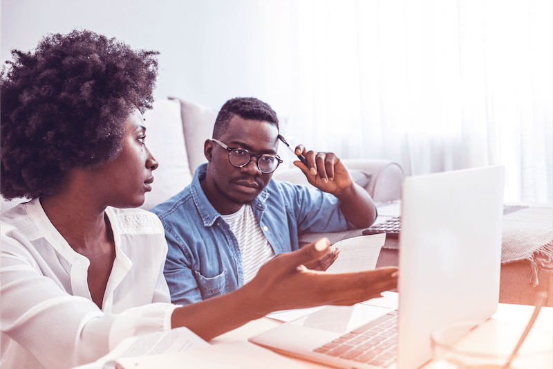 Man and woman looking at bills in front of laptop